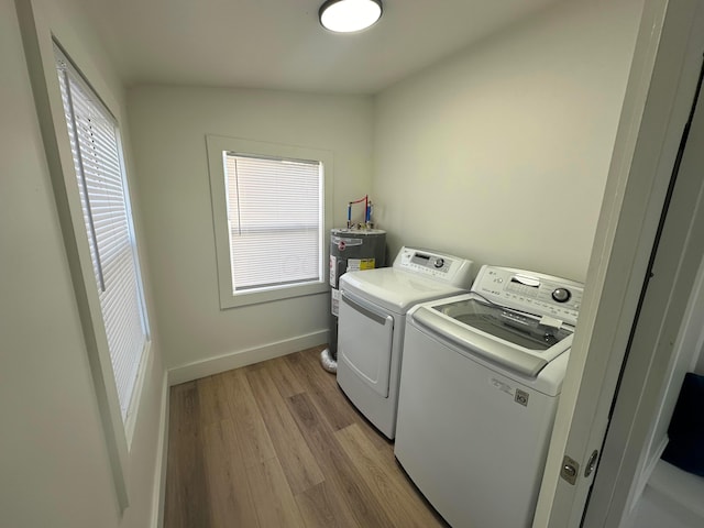 laundry area featuring light hardwood / wood-style flooring, washing machine and dryer, and electric water heater