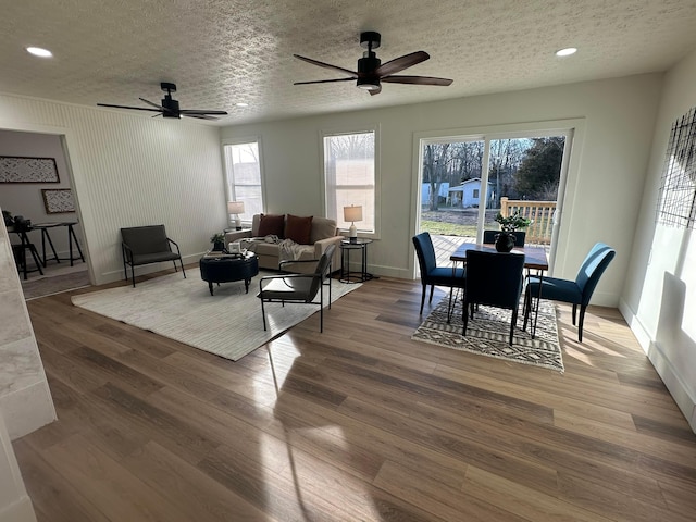 living room featuring hardwood / wood-style flooring, ceiling fan, and a textured ceiling