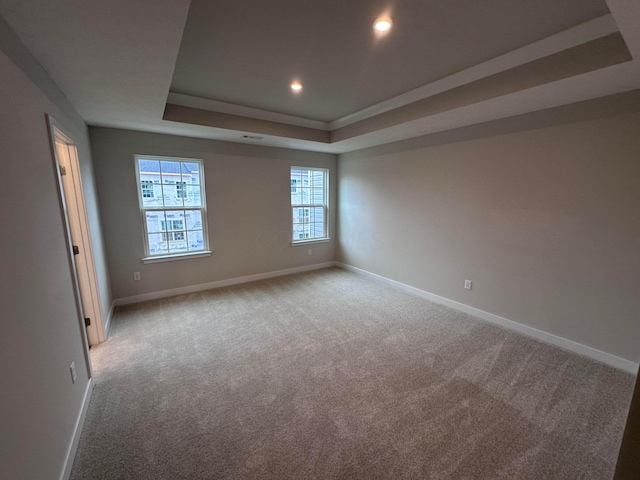 carpeted empty room featuring a tray ceiling