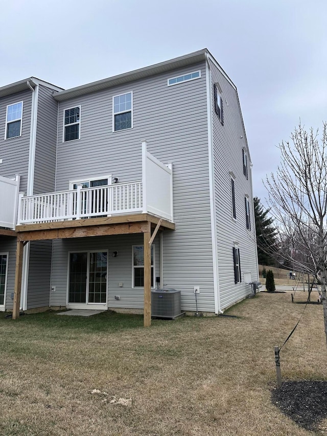 rear view of property featuring central AC, a lawn, and a deck