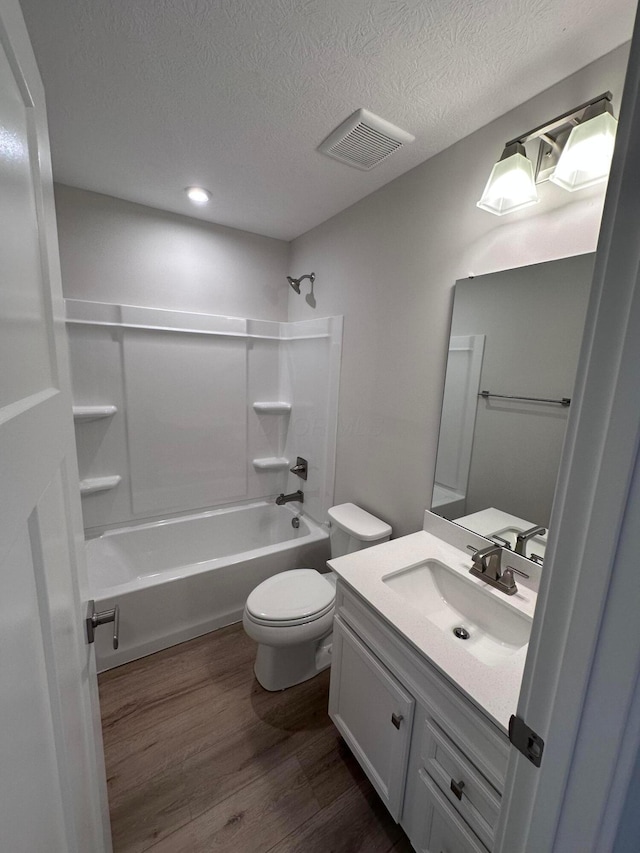 full bathroom with toilet, wood-type flooring, a textured ceiling, vanity, and shower / bath combination