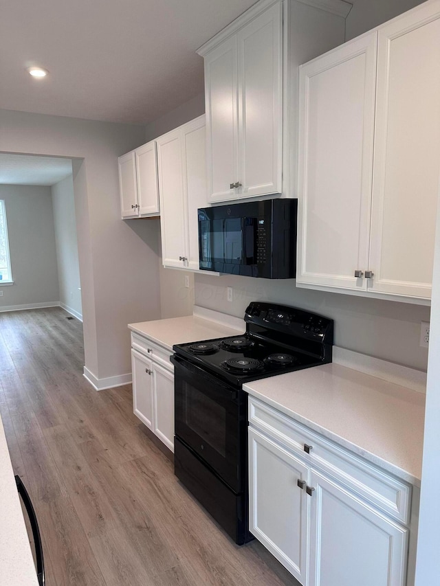 kitchen with white cabinetry, light hardwood / wood-style floors, and black appliances