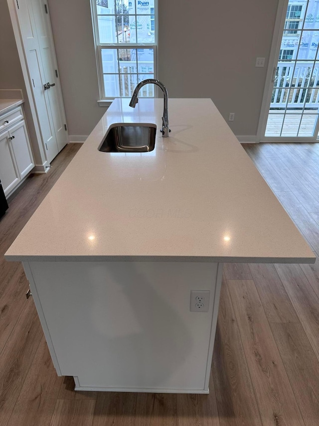 kitchen with a kitchen island with sink, sink, white cabinetry, and a wealth of natural light