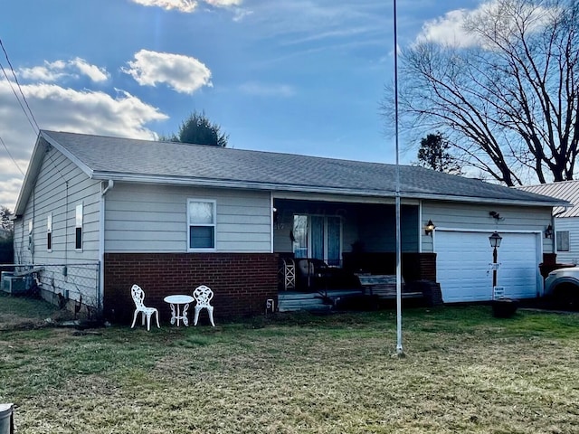 back of property with a garage and a lawn