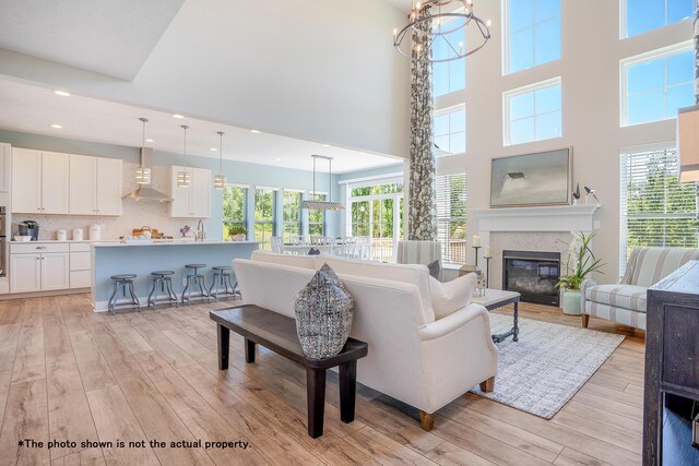 5467 Scotch Woods Dr, Grove City, OH 43123 - living area featuring light wood-type flooring, a towering ceiling, a healthy amount of sunlight, and a glass covered fireplace