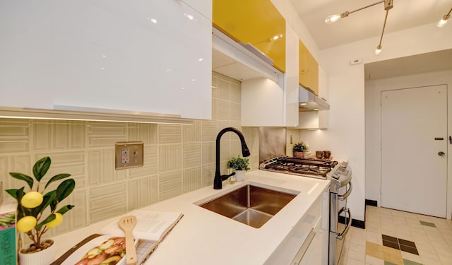 kitchen featuring range with two ovens, white cabinetry, sink, and backsplash