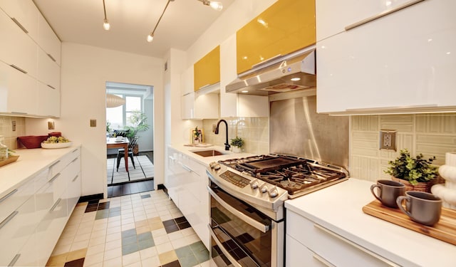 kitchen with white cabinetry, sink, exhaust hood, and range with two ovens