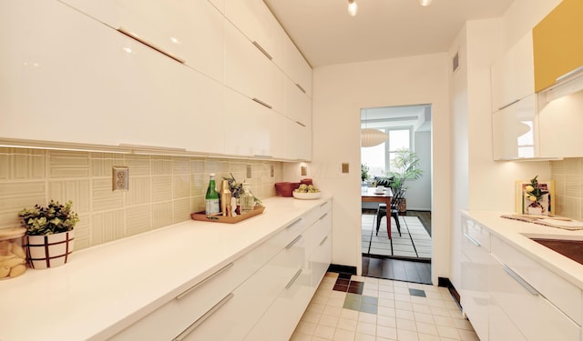 kitchen with tasteful backsplash, white cabinets, and light tile patterned flooring