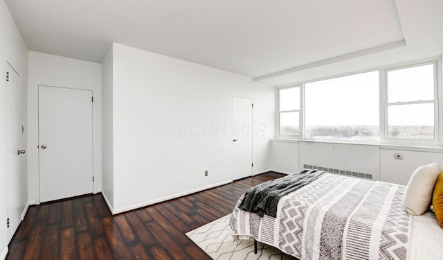 bedroom with dark wood-type flooring and radiator heating unit