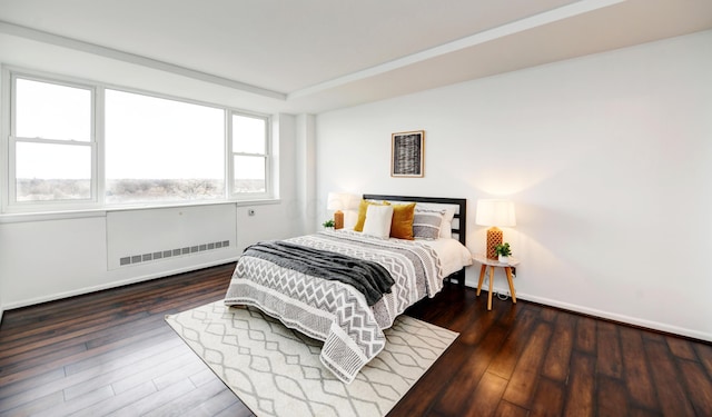 bedroom featuring radiator heating unit, a tray ceiling, and dark wood-type flooring