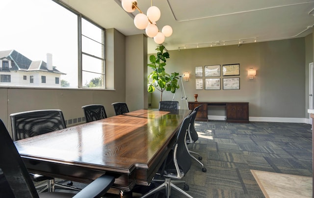 dining space featuring rail lighting and dark colored carpet