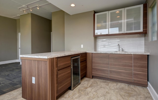 kitchen featuring rail lighting, sink, wine cooler, decorative backsplash, and kitchen peninsula