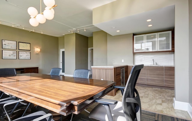 dining space with an inviting chandelier, rail lighting, and sink