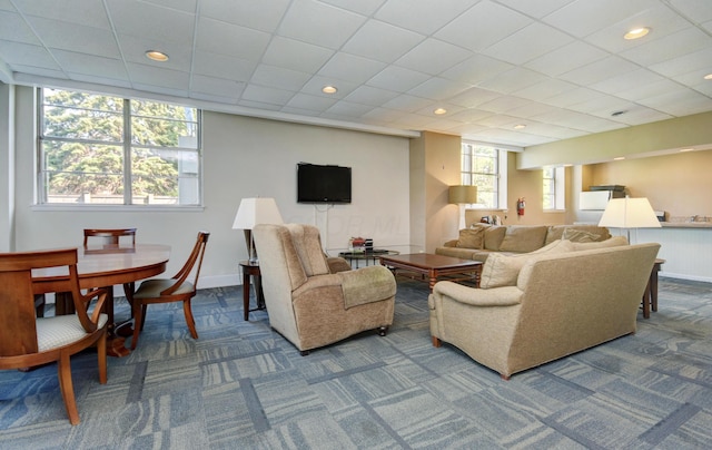 carpeted living room featuring a drop ceiling