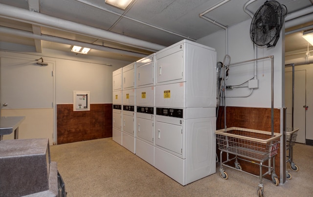 laundry room featuring stacked washer / dryer, a mail area, and wood walls