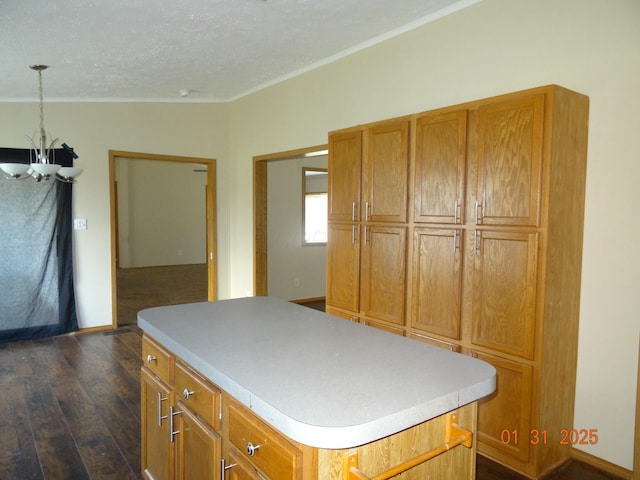 kitchen featuring decorative light fixtures, a center island, ornamental molding, dark hardwood / wood-style floors, and a notable chandelier