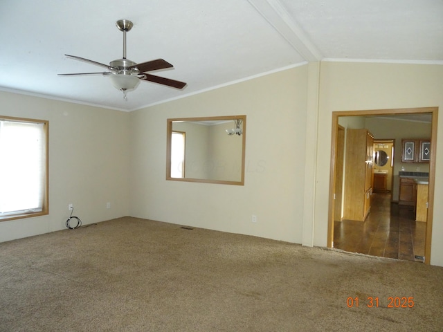 empty room with lofted ceiling, ornamental molding, ceiling fan, and dark colored carpet