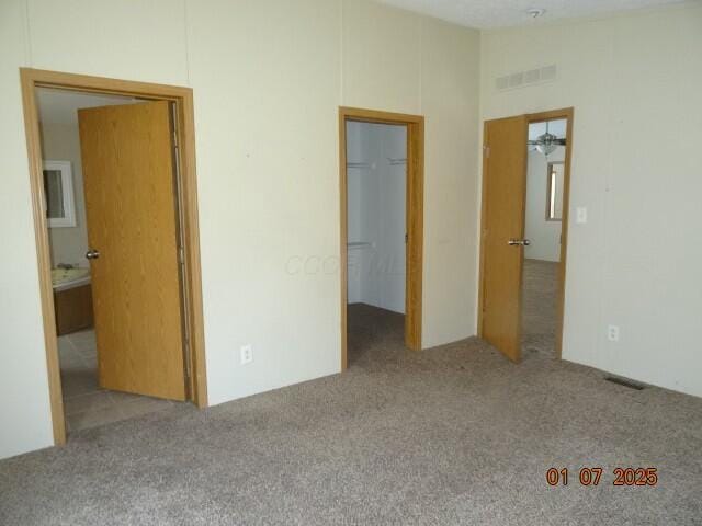 unfurnished bedroom with vaulted ceiling, a walk in closet, and light carpet