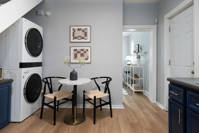 washroom with stacked washing maching and dryer and light hardwood / wood-style flooring