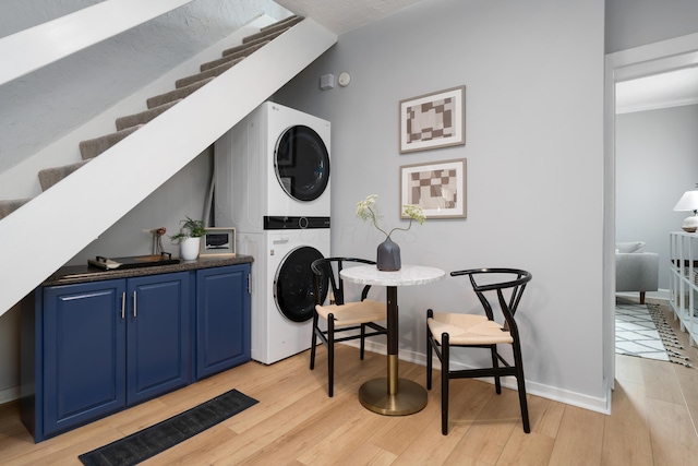 laundry room with stacked washer and dryer and light hardwood / wood-style floors