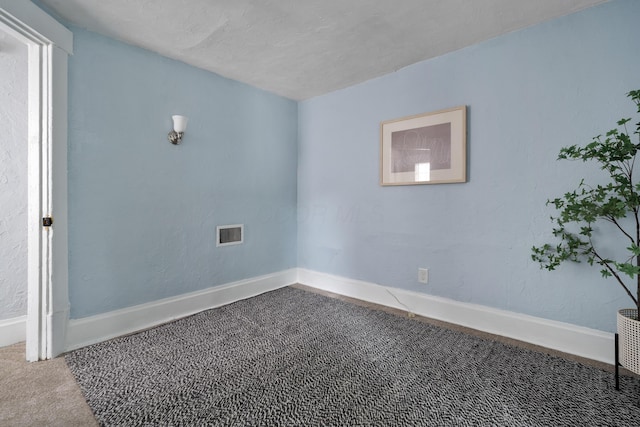 carpeted empty room featuring a textured ceiling