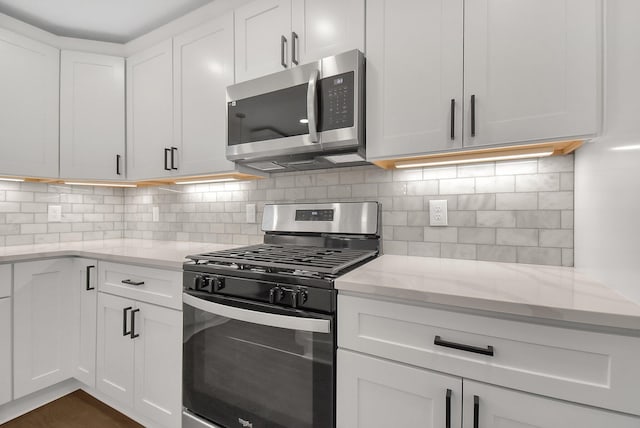 kitchen featuring light stone counters, decorative backsplash, white cabinets, and appliances with stainless steel finishes