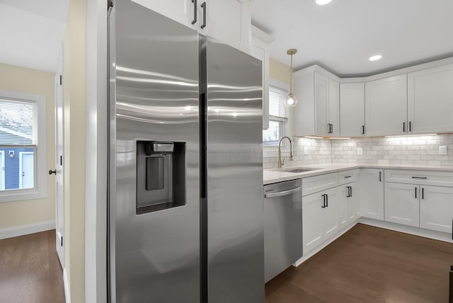 kitchen featuring hanging light fixtures, appliances with stainless steel finishes, sink, and white cabinets