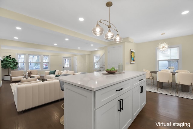 kitchen with decorative light fixtures, dark hardwood / wood-style floors, a kitchen island, a healthy amount of sunlight, and white cabinets