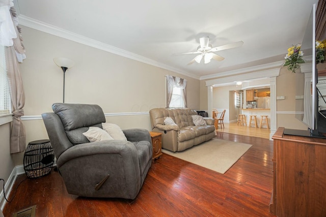 living room with decorative columns, crown molding, dark hardwood / wood-style floors, and ceiling fan