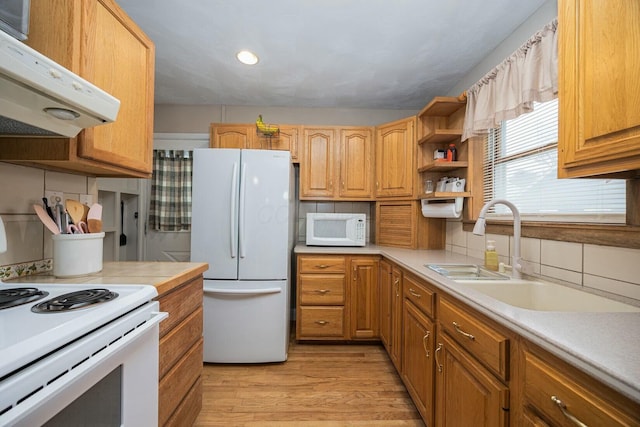 kitchen with sink, white appliances, light hardwood / wood-style floors, and decorative backsplash