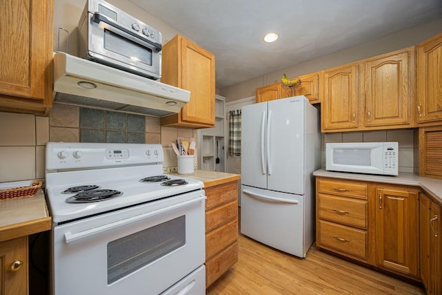 kitchen with light hardwood / wood-style flooring, white appliances, and decorative backsplash