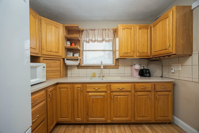 kitchen featuring sink, white appliances, light hardwood / wood-style floors, and backsplash