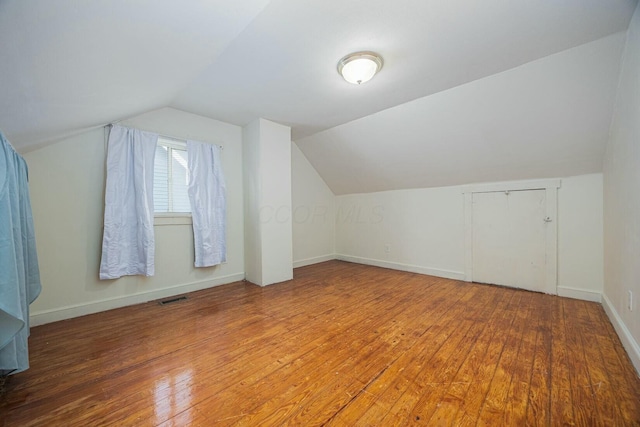 additional living space with hardwood / wood-style floors and vaulted ceiling