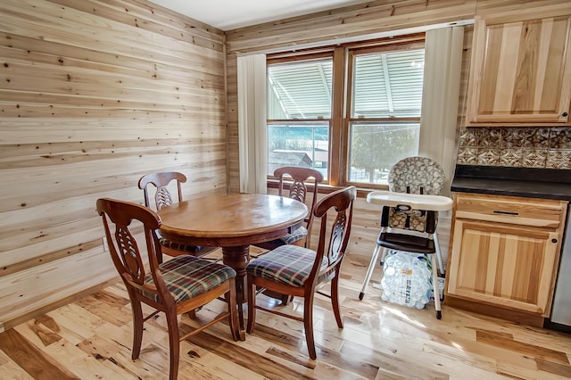 dining space featuring light hardwood / wood-style floors and wood walls