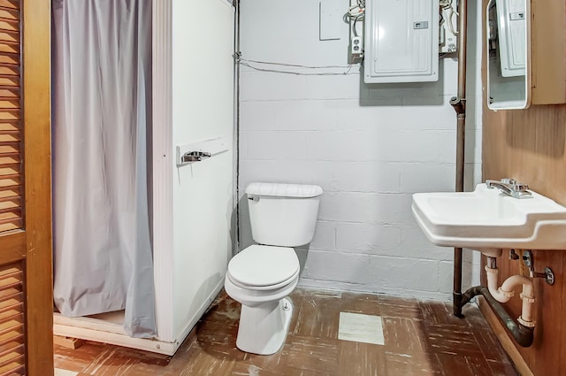 bathroom featuring toilet, electric panel, and sink