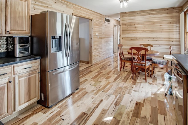 kitchen with wooden walls, stainless steel fridge with ice dispenser, light brown cabinets, and light wood-type flooring