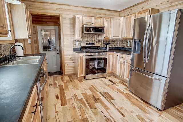 kitchen with appliances with stainless steel finishes, sink, decorative backsplash, light hardwood / wood-style floors, and light brown cabinets