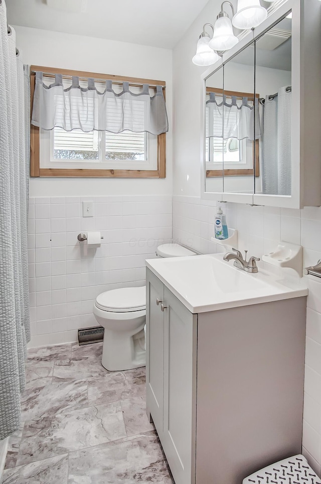 bathroom featuring vanity, tile walls, and toilet