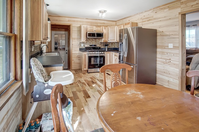 kitchen featuring stainless steel appliances, wooden walls, sink, and light brown cabinets