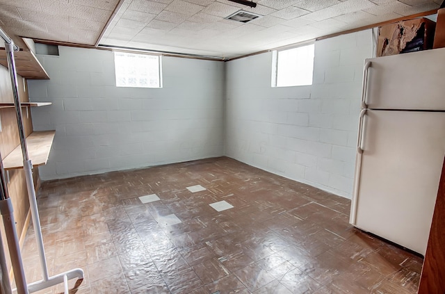 basement with a wealth of natural light and white refrigerator