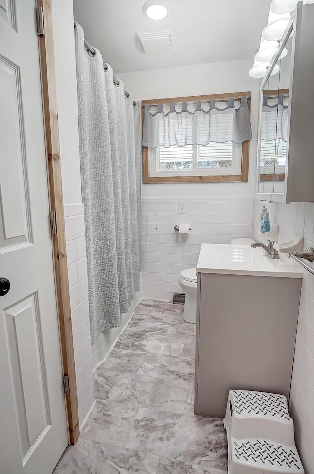 bathroom featuring a shower with curtain, vanity, toilet, and tile walls