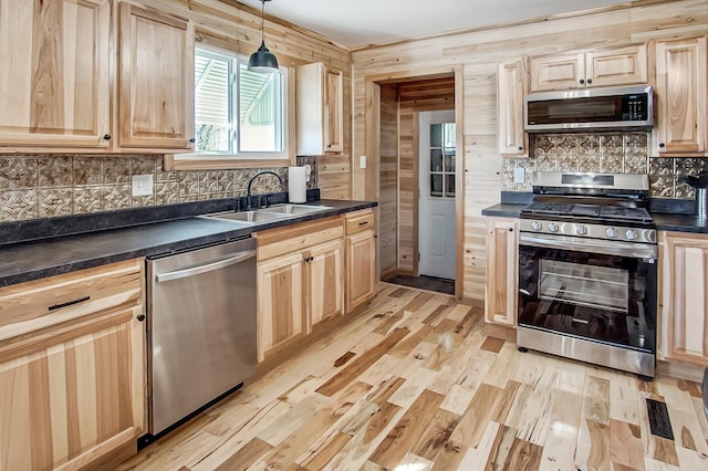 kitchen featuring sink, decorative light fixtures, light wood-type flooring, appliances with stainless steel finishes, and backsplash