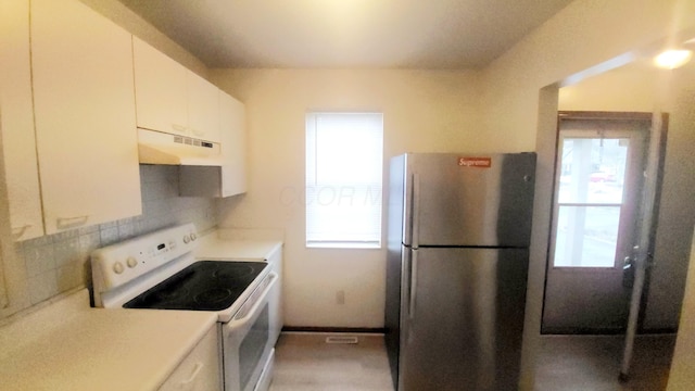 kitchen featuring white electric range oven, white cabinetry, tasteful backsplash, ventilation hood, and stainless steel fridge