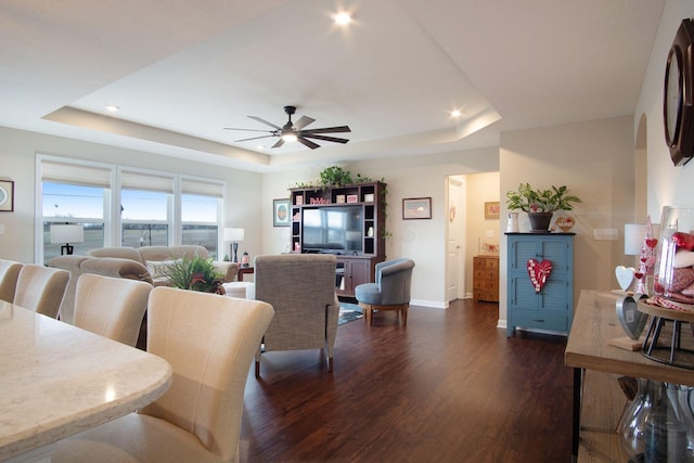 living room with dark hardwood / wood-style floors, ceiling fan, and a tray ceiling