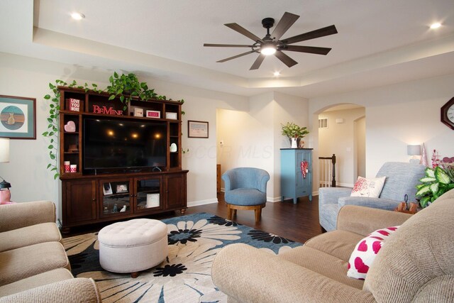 living room featuring ceiling fan, dark hardwood / wood-style floors, and a raised ceiling