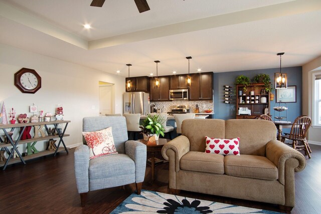 living room featuring ceiling fan with notable chandelier and dark hardwood / wood-style floors