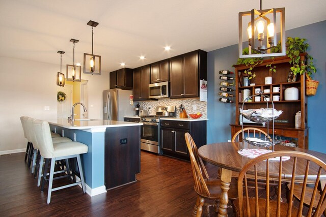 kitchen featuring sink, dark wood-type flooring, stainless steel appliances, tasteful backsplash, and decorative light fixtures