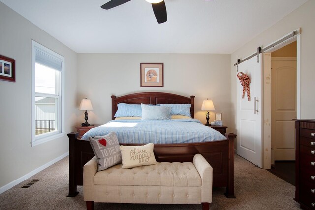 bedroom with ceiling fan, a barn door, and carpet floors