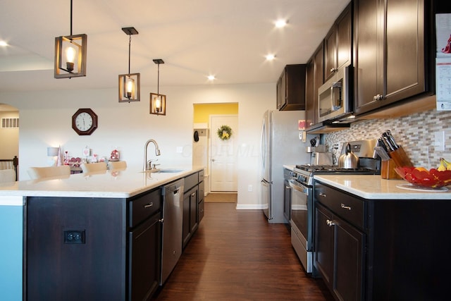 kitchen with pendant lighting, an island with sink, stainless steel appliances, and sink