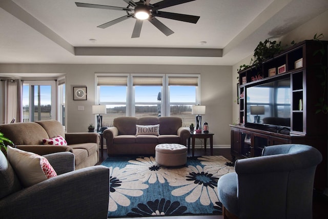 living room with hardwood / wood-style flooring, ceiling fan, a tray ceiling, and a wealth of natural light